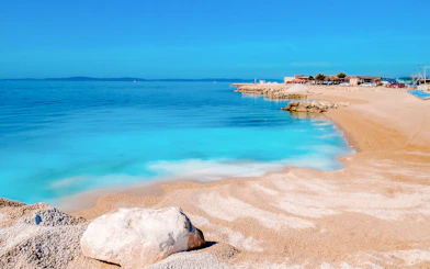 Beach with crystal blue water and rocky shoreline near Split, Croatia.