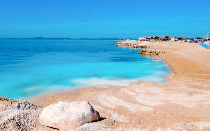 Beach with crystal blue water and rocky shoreline near Split, Croatia.