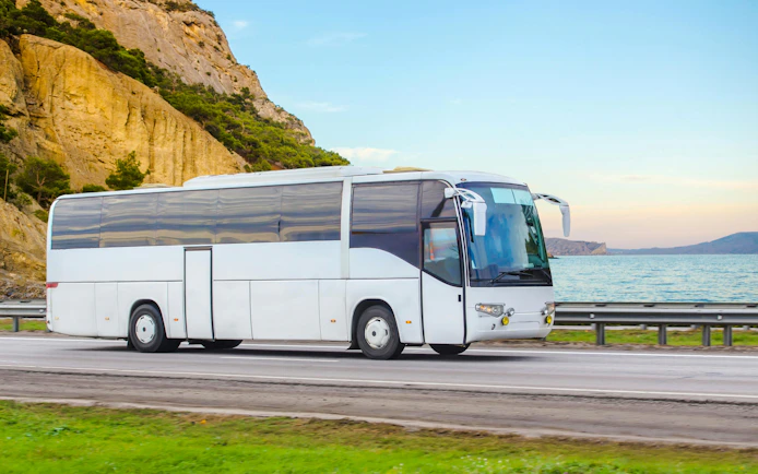 Bus on coastal road for Cape Sounio and Poseidon Temple trip transfers.