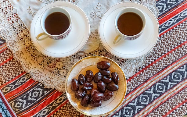 Traditional Arabian coffee with dates on a patterned tablecloth.