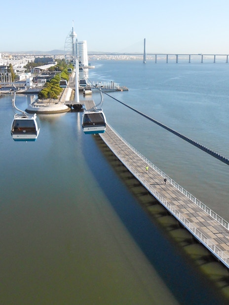 Lisbon cable cars over Tagus River near Oceanarium and Vasco da Gama Bridge.