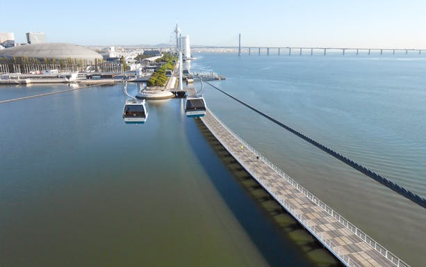 Lisbon cable cars over Tagus River near Oceanarium and Vasco da Gama Bridge.