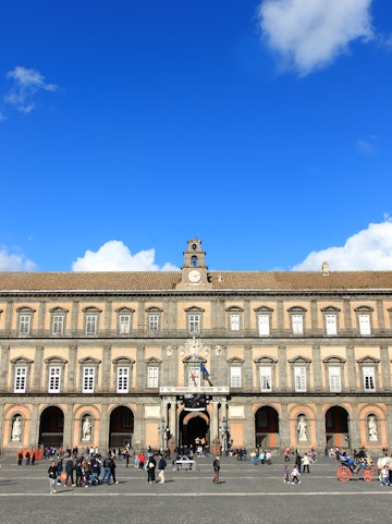 Palazzo Reale in Naples with visitors in the courtyard.