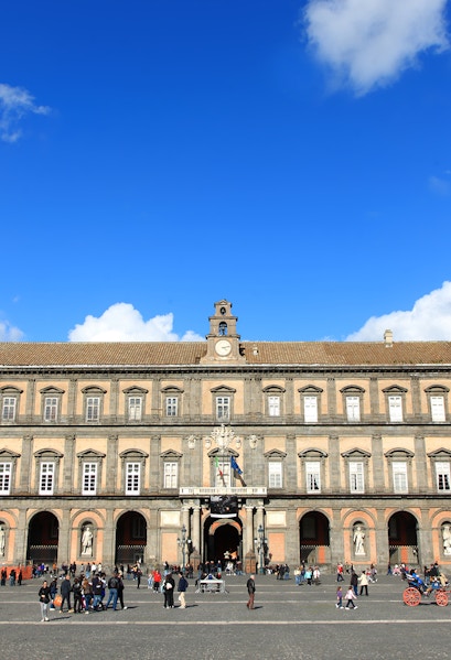 Palazzo Reale in Naples with visitors in the courtyard.