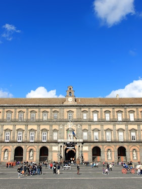 Palazzo Reale in Naples with visitors in the courtyard.