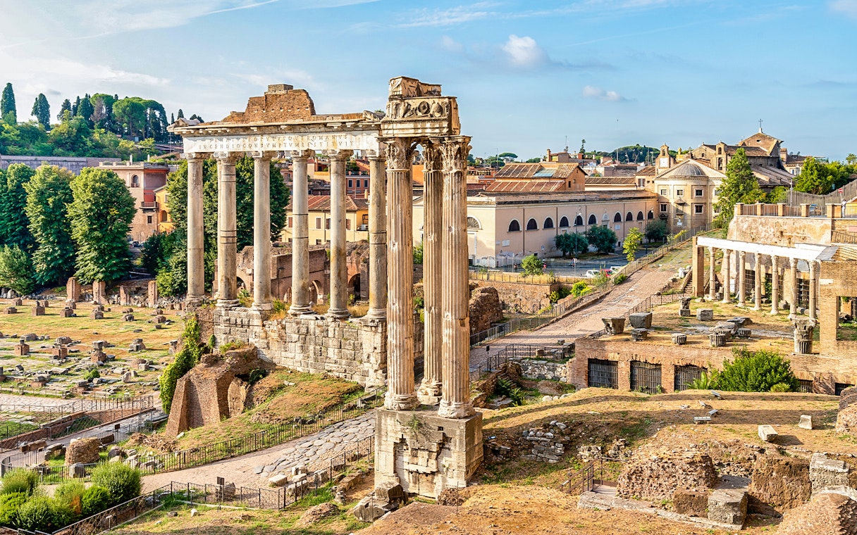 Ancient ruins and columns on Palatine Hill, Rome, with cityscape in the background.