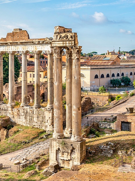 Ancient ruins and columns on Palatine Hill, Rome, with cityscape in the background.