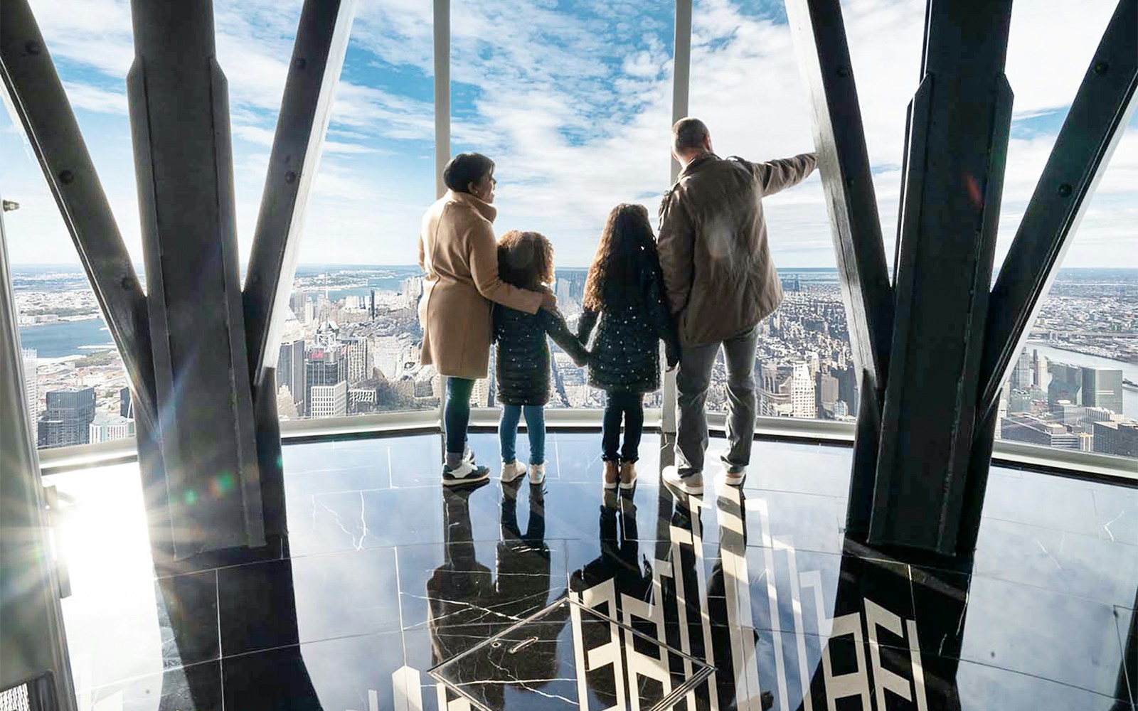 Family viewing New York City skyline from Empire State Building observatory.