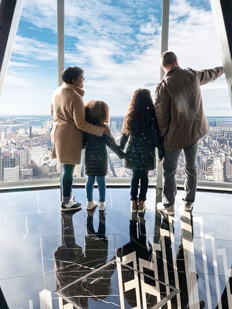 Family viewing New York City skyline from Empire State Building observatory.