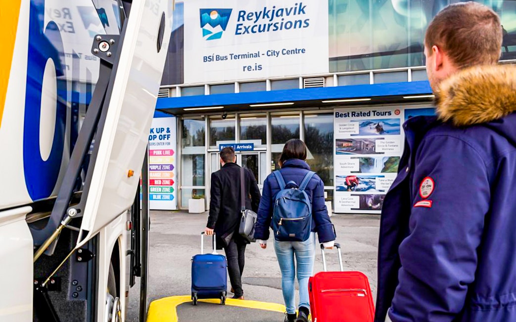 Tourists with luggage enter Reykjavik Excursions bus terminal.