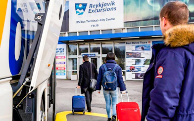 Tourists with luggage enter Reykjavik Excursions bus terminal.