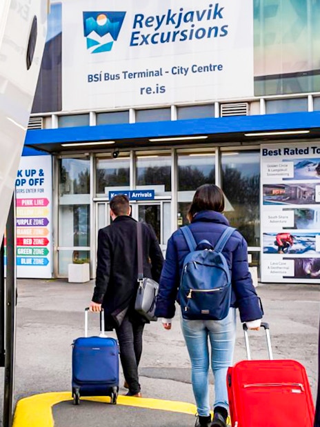 Tourists with luggage enter Reykjavik Excursions bus terminal.