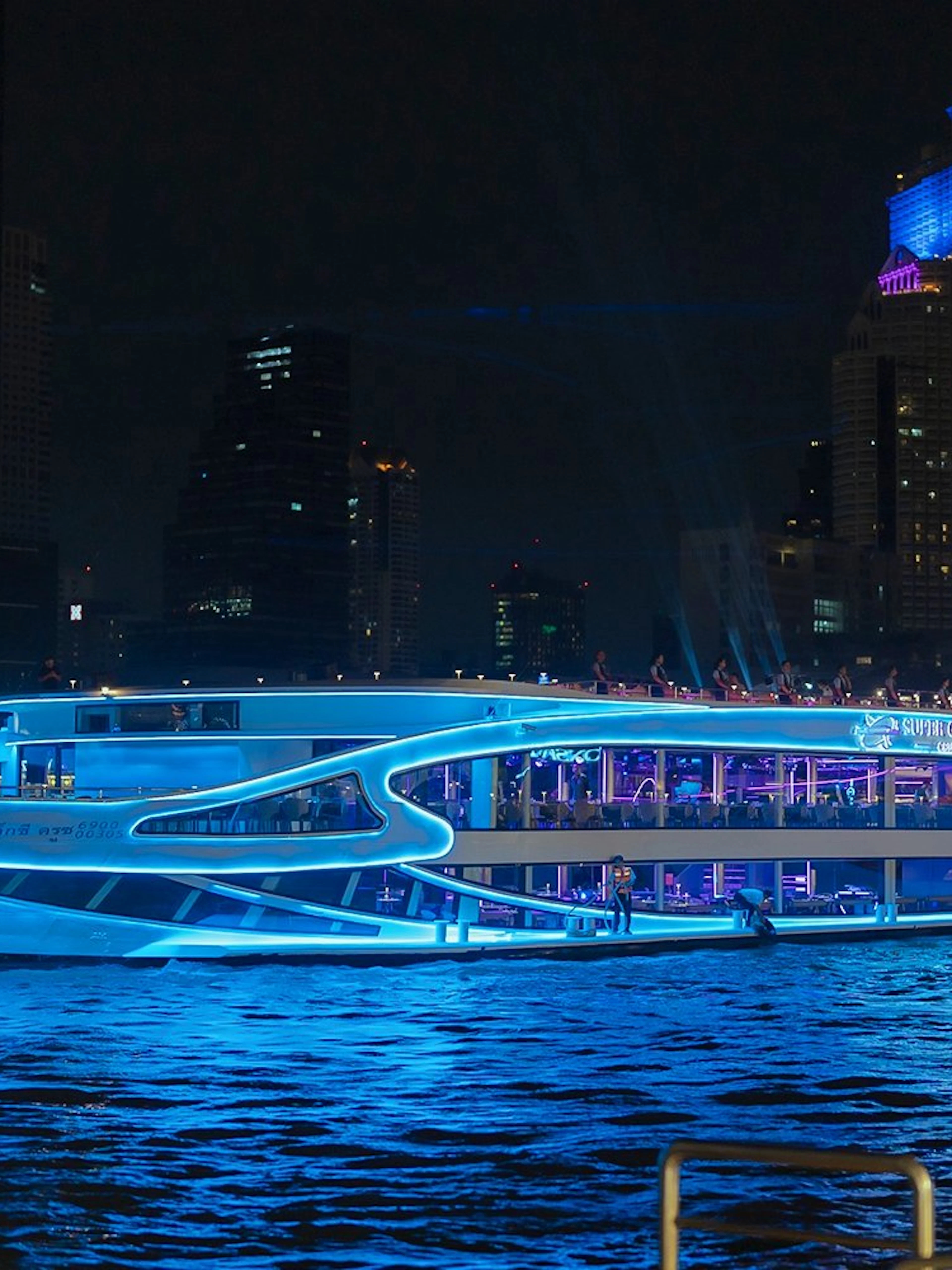 Luxury dinner cruise on Chao Phraya River, Bangkok, with city skyline at night.