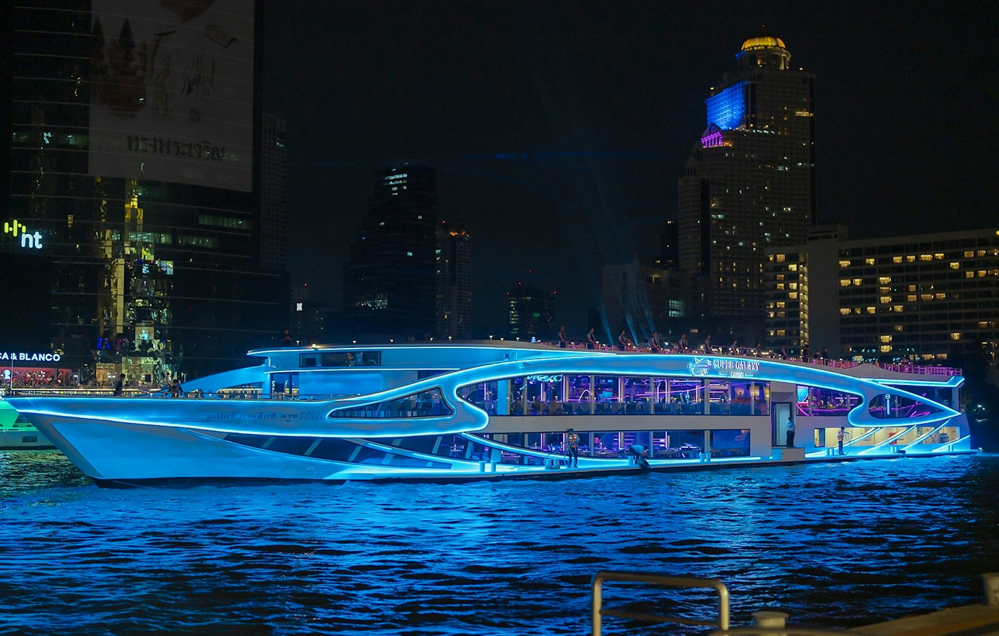 Luxury dinner cruise on Chao Phraya River, Bangkok, with city skyline at night.