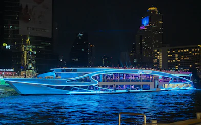 Luxury dinner cruise on Chao Phraya River, Bangkok, with city skyline at night.