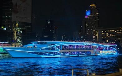 Luxury dinner cruise on Chao Phraya River, Bangkok, with city skyline at night.