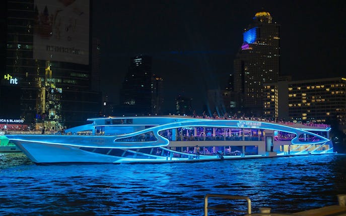 Luxury dinner cruise on Chao Phraya River, Bangkok, with city skyline at night.