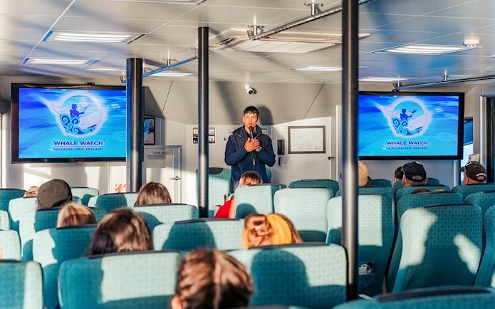Guide giving a presentation on a whale watching cruise in Kaikoura, New Zealand.
