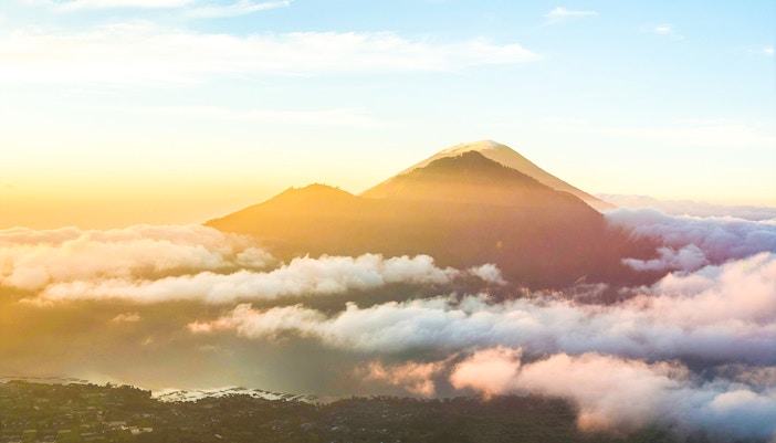 Mount Batur in Bali surrounded by clouds at sunrise.