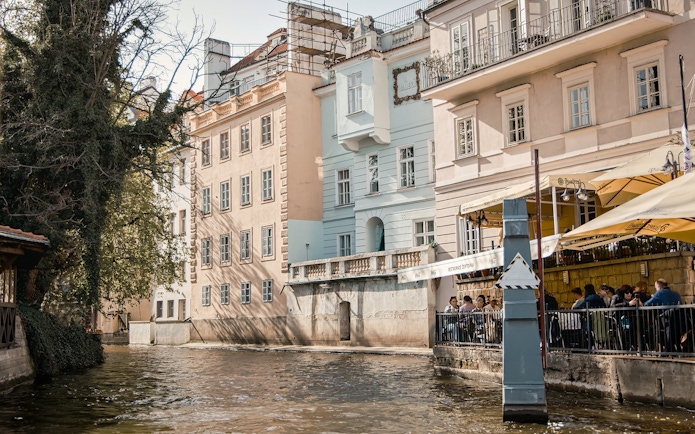 Riverside view of historic buildings and outdoor café along the Vltava River in Prague Old Town.
