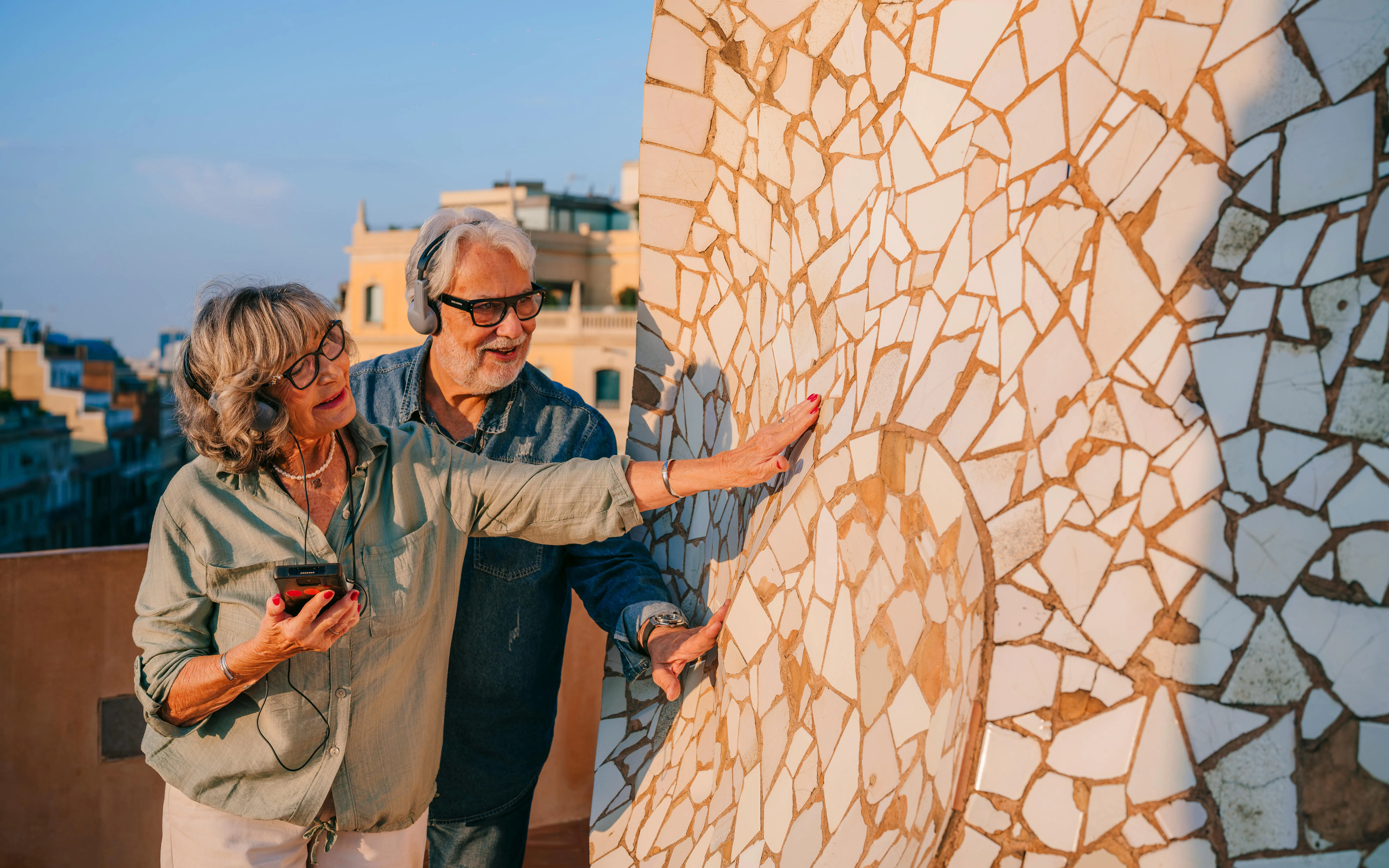 Couple exploring mosaic details on La Pedrera rooftop during sunset visit in Barcelona.