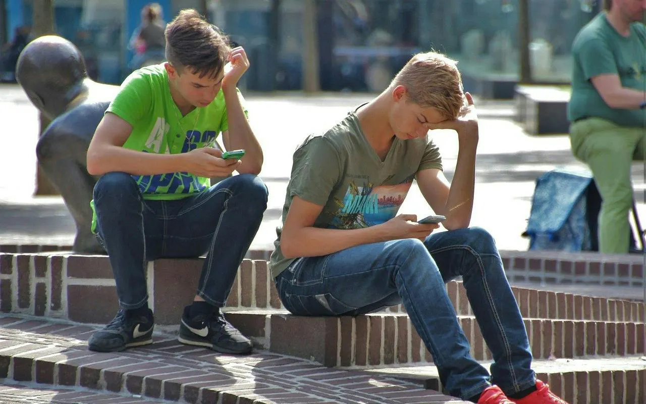 Two people sitting on steps, engaged with phones, part of New Orleans city exploration game.