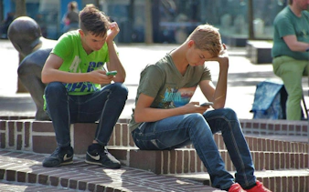 Two people sitting on steps, engaged with phones, part of New Orleans city exploration game.