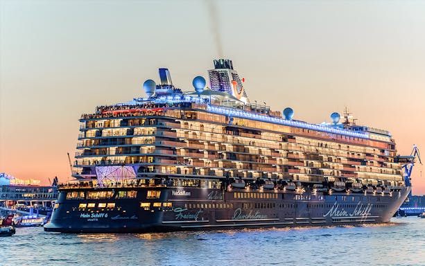 Large cruise ship illuminated at sunset during a 1.5h Grand Evening Lights Cruise.