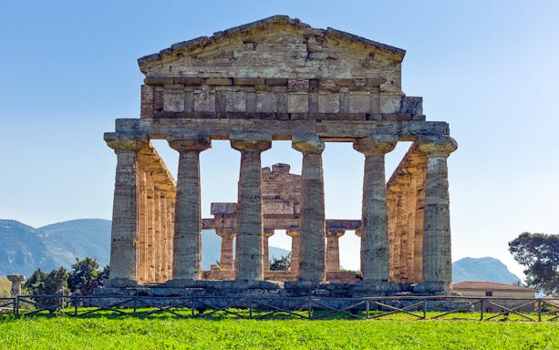 Temple of Athena ruins at Paestum archaeological site, Campania, with ancient columns and clear sky.