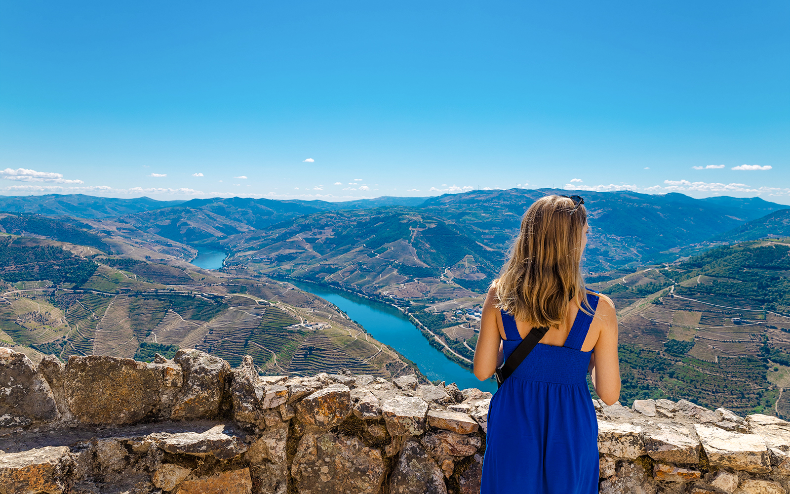 Tourist admiring Douro Valley landscape from a scenic viewpoint in Portugal.