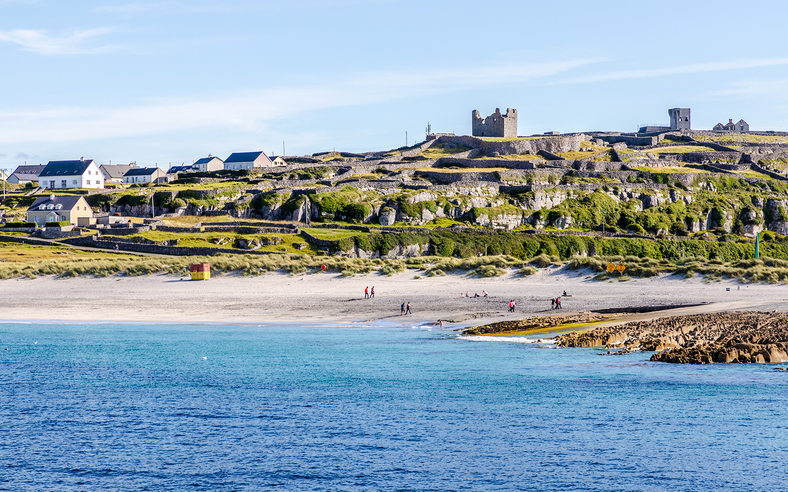 Inisheer Island beach with stone walls and castle ruins, Ireland.