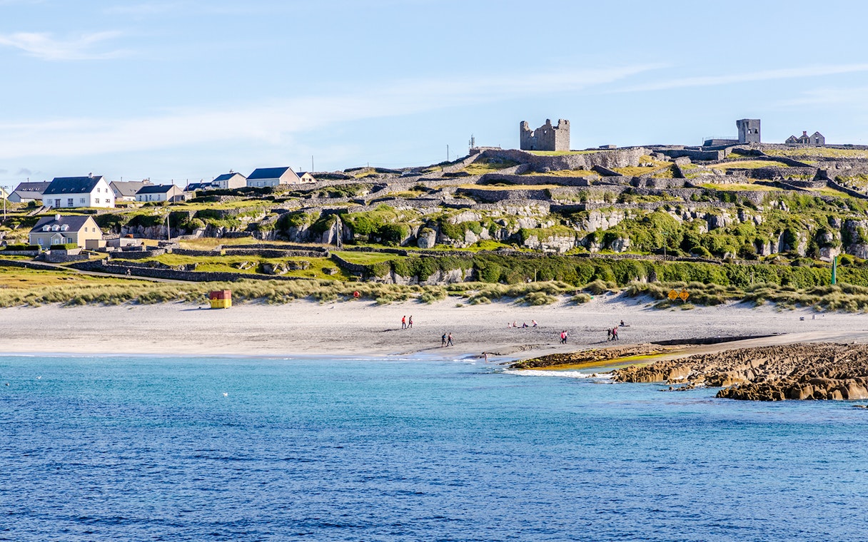 Inisheer Island beach with stone walls and castle ruins, Ireland.