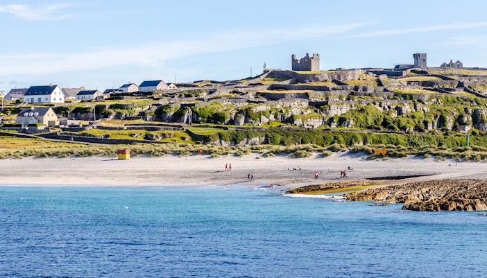 Inisheer Island beach with stone walls and castle ruins, Ireland.