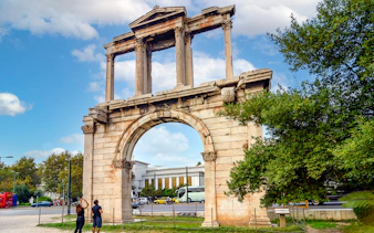 The Arch of Hadrian in Athens with tourists taking photos.