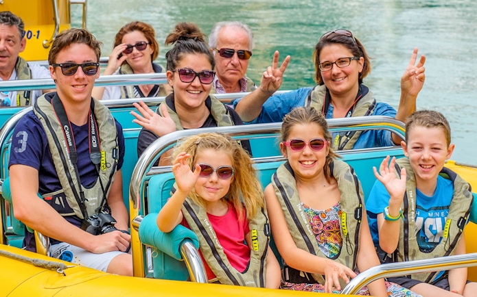 People smiling and waving on a Yellow Boats tour in Dubai.