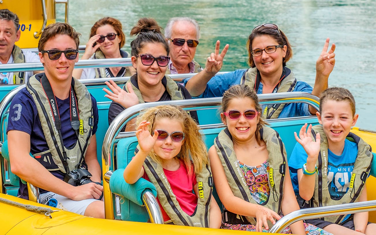 People smiling and waving on a Yellow Boats tour in Dubai.