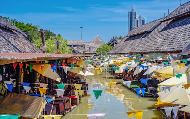 Pattaya Floating Market with colorful flags and traditional wooden shops along the canal.