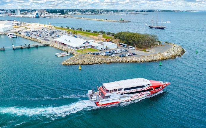 Rottnest Express ferry leaving jetty with cars and buildings in Fremantle, Australia.