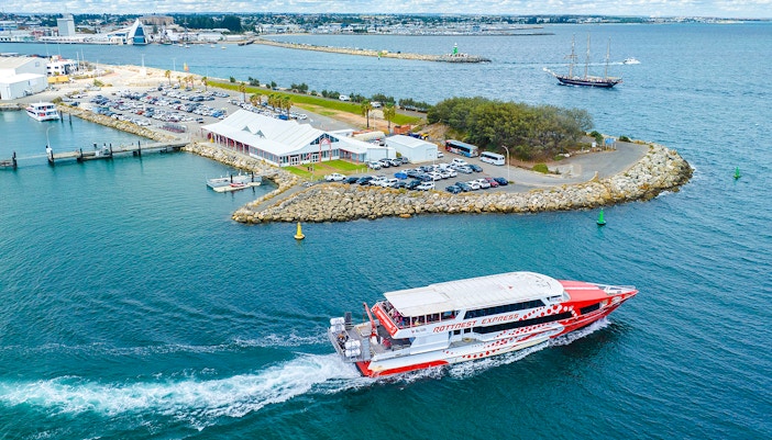 Rottnest Express ferry leaving jetty with cars and buildings in Fremantle, Australia.