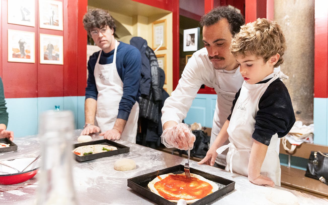 Participants in a Rome kitchen making pizza and tiramisu during a cooking class.