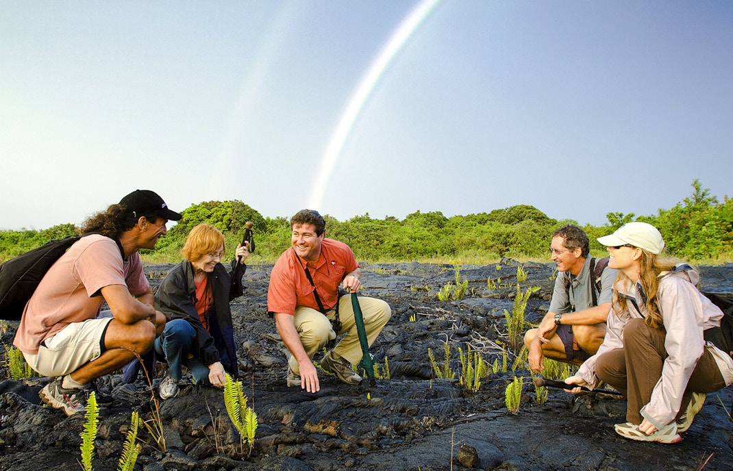 Guests exploring volcanic terrain under a rainbow on Hawaii adventure tour.