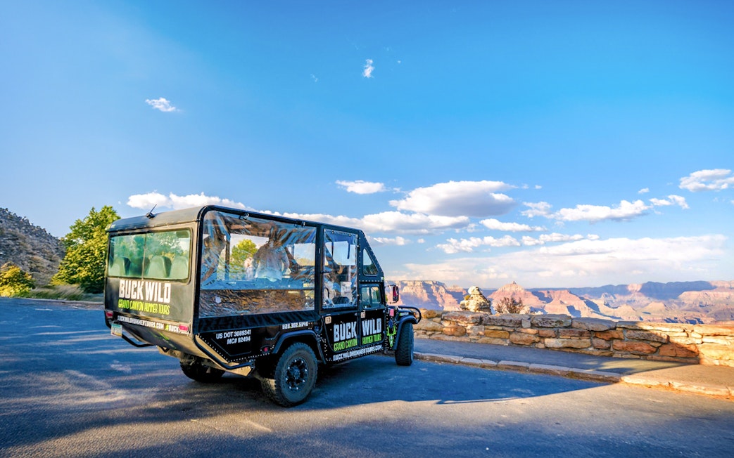 Hummer parked at Grand Canyon viewpoint with scenic canyon backdrop.