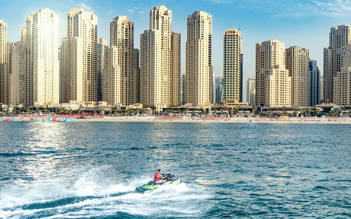 Jet ski rider on Dubai waters with city skyline in the background.