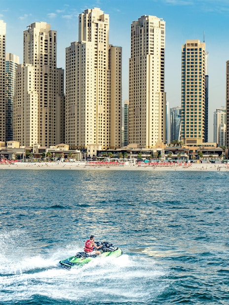 Jet ski rider on Dubai waters with city skyline in the background.