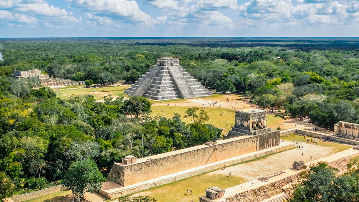 Aerial view of Chichen Itza with El Castillo pyramid surrounded by lush greenery.