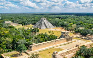 Aerial view of Chichen Itza with El Castillo pyramid surrounded by lush greenery.