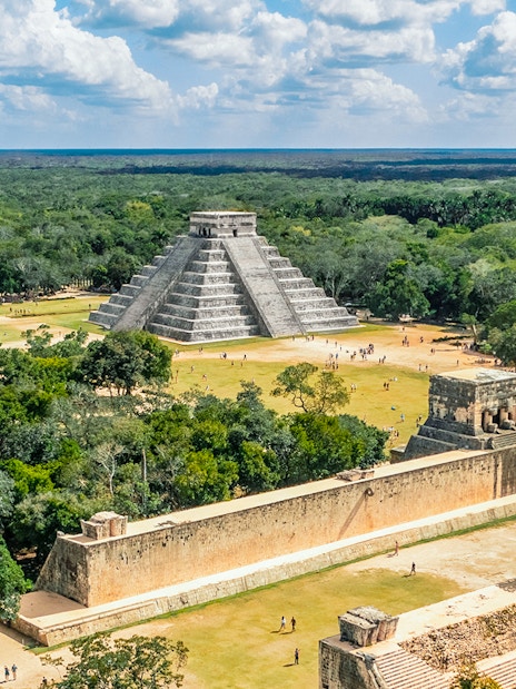 Aerial view of Chichen Itza with El Castillo pyramid surrounded by lush greenery.