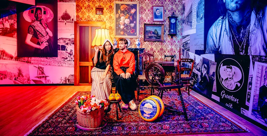 Guests in traditional Dutch attire at a Holland-themed exhibit with tulips and cheese.