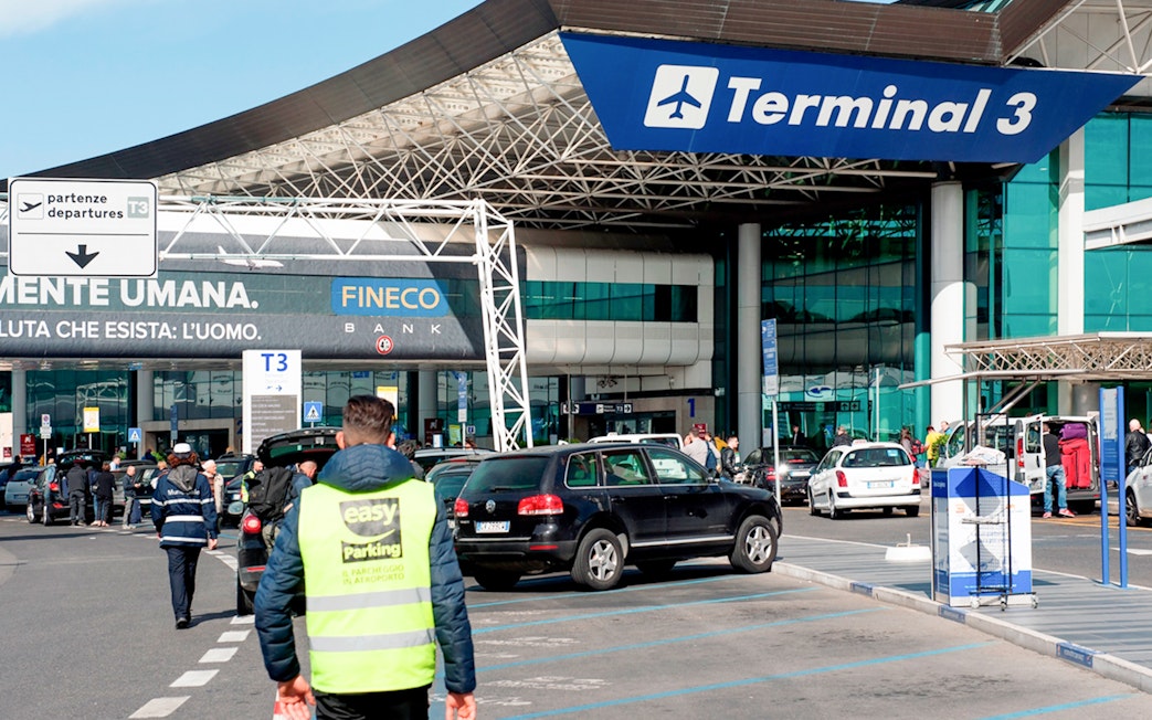 Fiumicino Airport Terminal 3 entrance with cars and travelers, Rome, Italy.