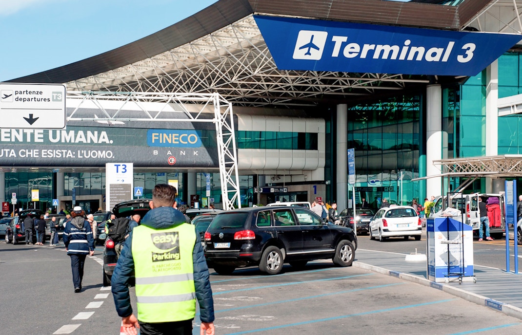 Fiumicino Airport Terminal 3 entrance with cars and travelers, Rome, Italy.